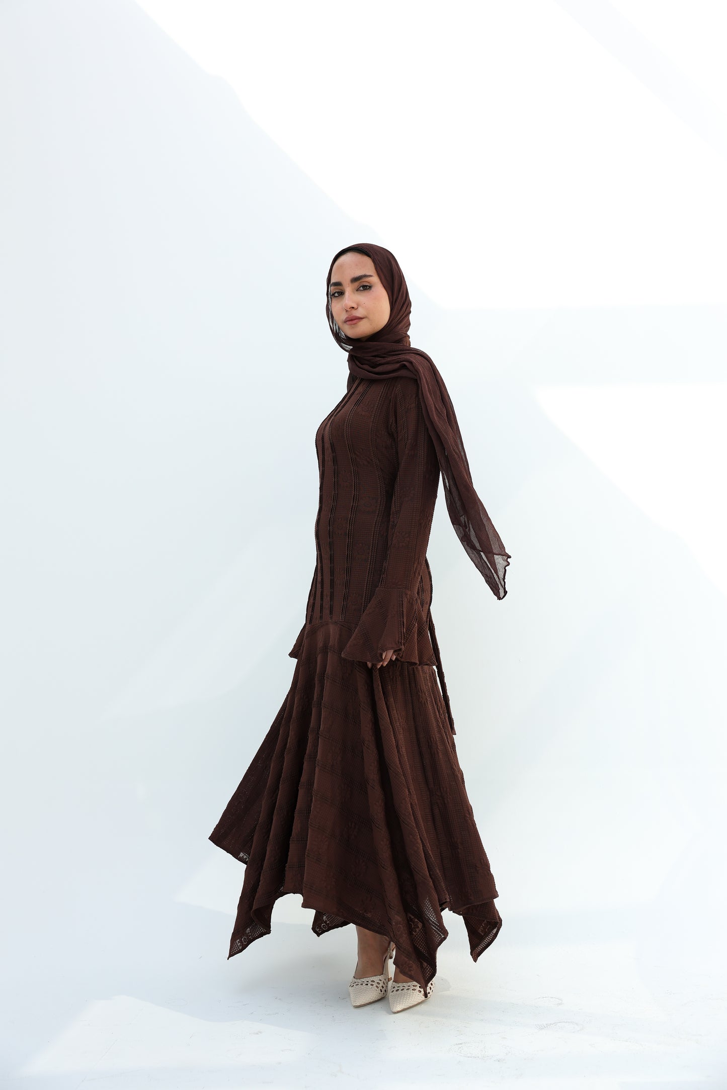lace dress with a unique design in brown , fully lined." فستان من الدانتيل الفاخرباللون البني، يجسد براعة التصميم بتفاصيل فريدة وبطانة كامله ناعمة تمنحكِ رقياً لا يضاهى."